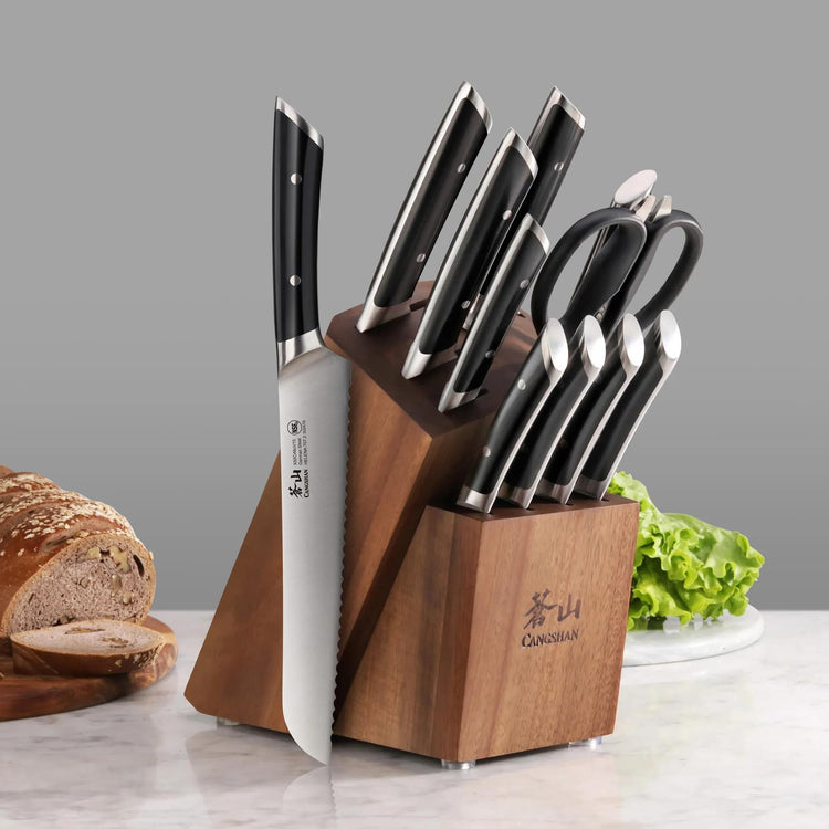 12-piece knife set with black handles in a wooden block, including a bread knife, scissors, and various kitchen knives.