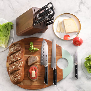 
                    
                      Wooden knife block with six knives, three knives on a cutting board with bread, tomato, and lettuce, and a plate with cheese
                    
                  