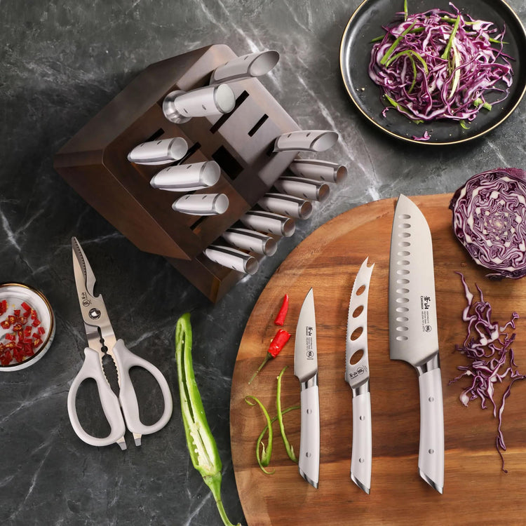 17-piece knife block set with white-handled knives, kitchen shears, and acacia wood block on a dark countertop with chopped v
