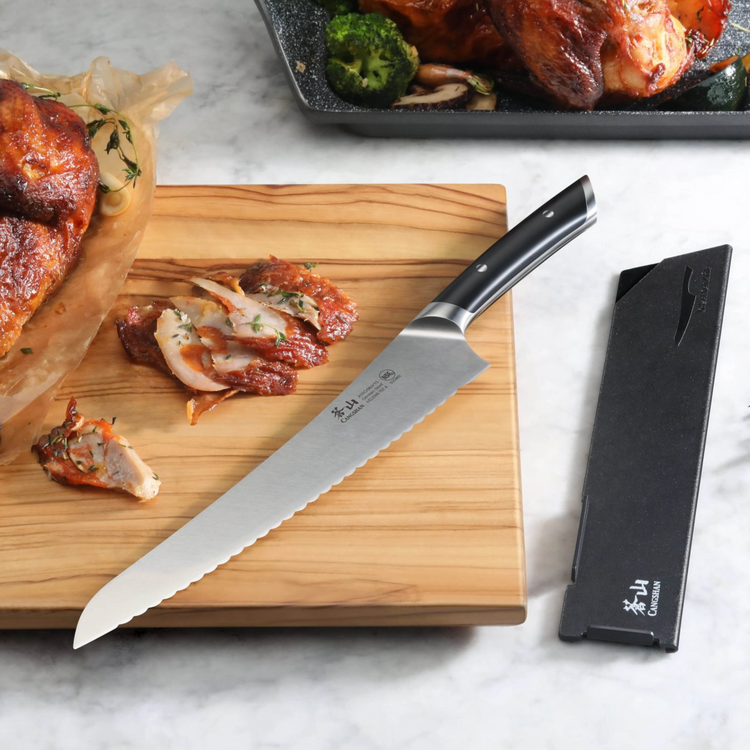9-inch serrated deli knife with black handle on wooden cutting board next to sliced roasted chicken and knife sheath.