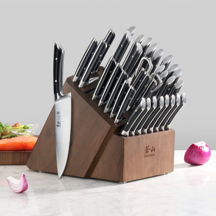 Wooden knife block set holding various black-handled knives and kitchen shears on a marble countertop.