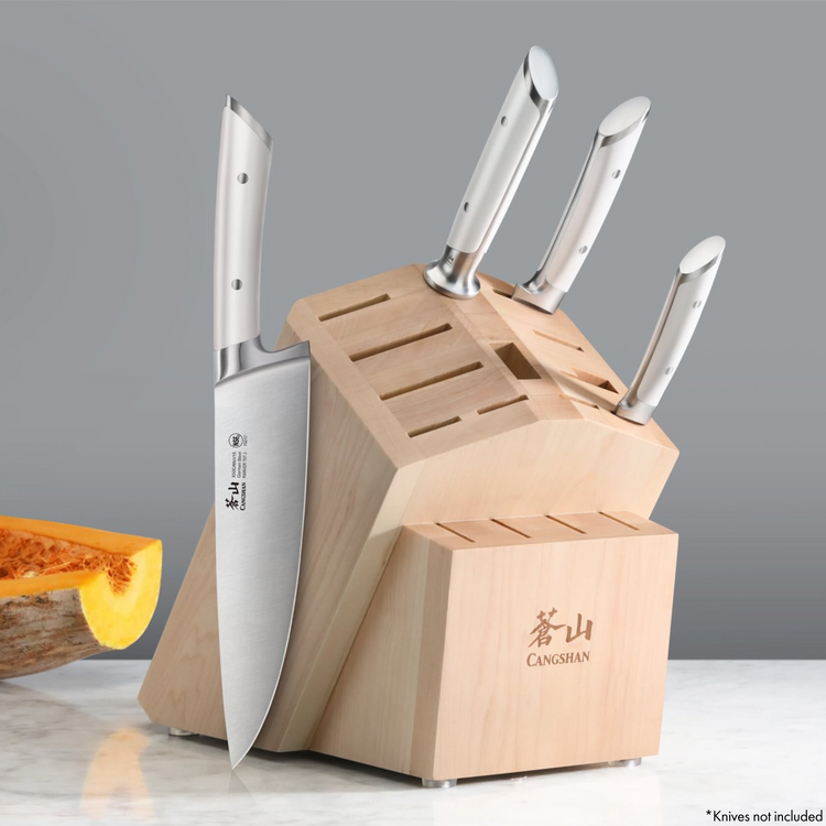Maple knife block with 16 slots, holding four knives with white handles, on a marble surface.