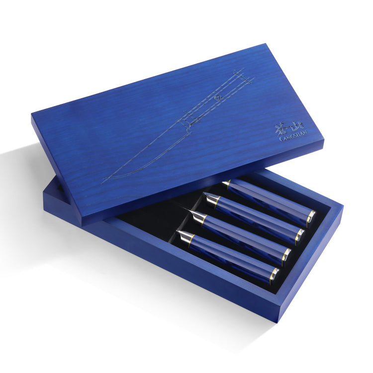 Four steak knives with blue handles in a partially open blue wooden box with engraved knife outline on the lid.