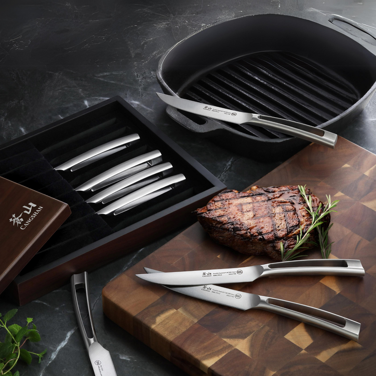 Eight-piece steak knife set with stainless steel blades and handles, displayed with grilled steak on a wooden cutting board.