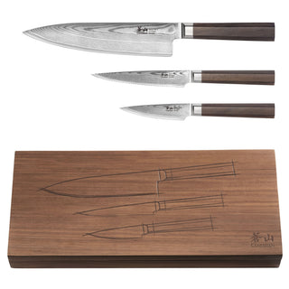 
                    
                      Three Damascus steel knives with wooden handles displayed above a walnut wood box with knife outlines engraved on the lid.
                    
                  