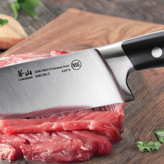 
                    
                      Close-up of a German steel chef's knife cutting raw red meat on a wooden board.
                    
                  