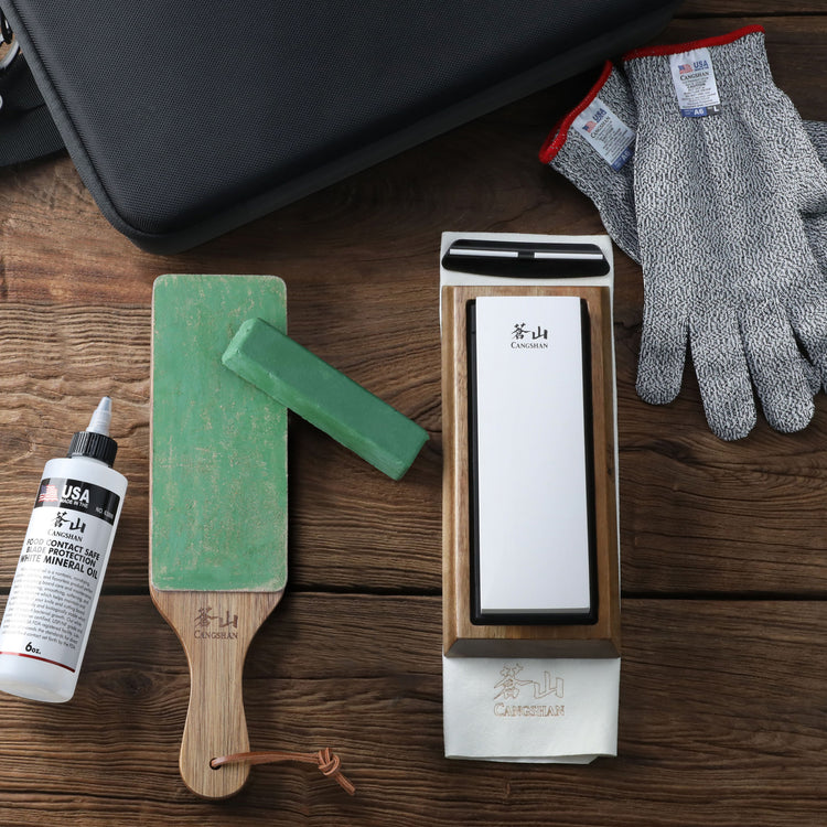 Whetstone sharpener on wooden base with sharpening guide, green honing stone, cut-resistant gloves, oil bottle, and carrying