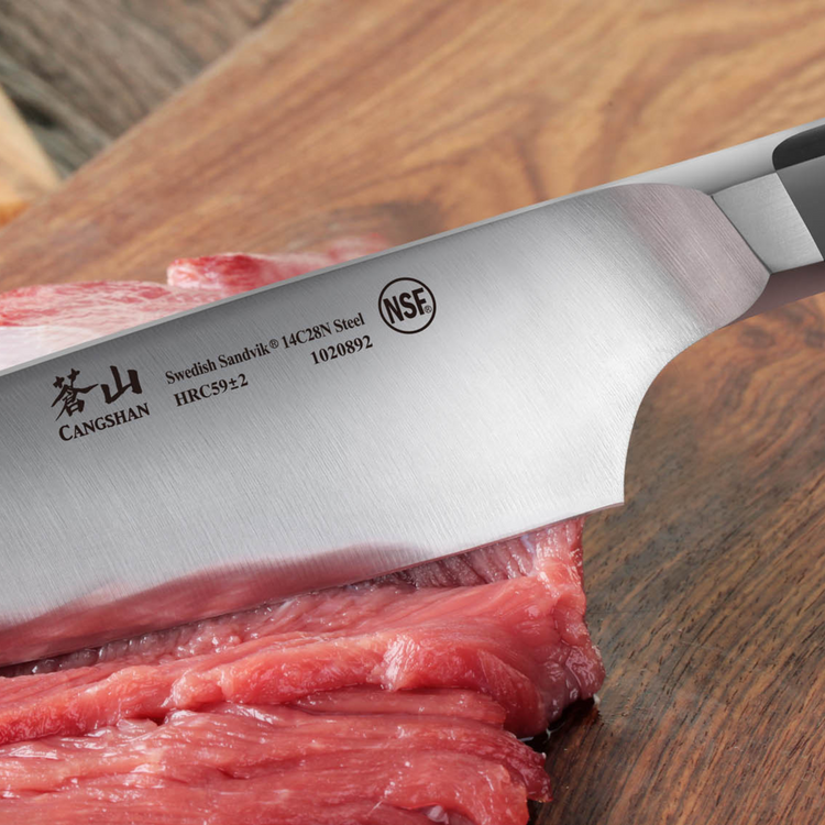 Close-up of a chef knife slicing raw red meat on a wooden cutting board.