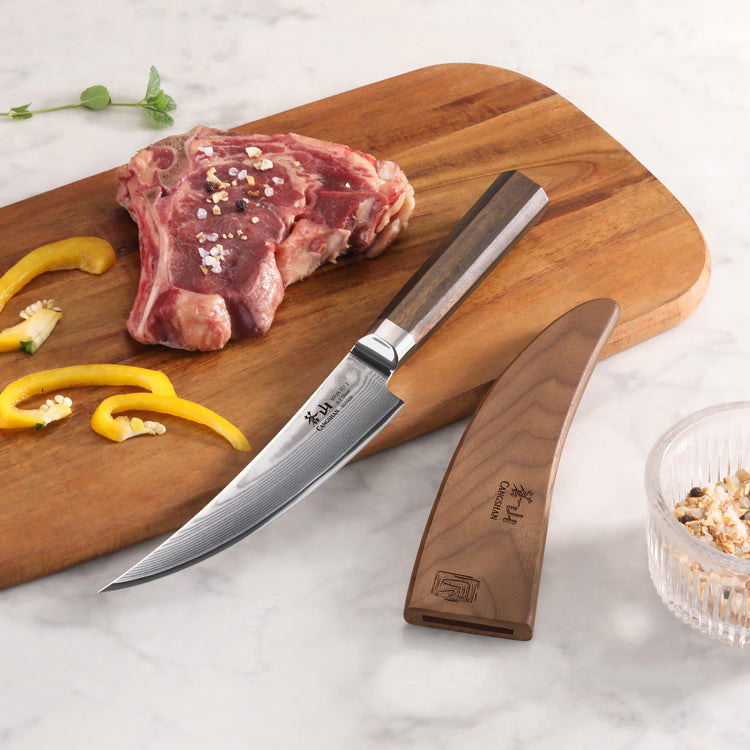 6-inch boning knife with wooden handle and sheath on cutting board next to raw meat and sliced yellow peppers.