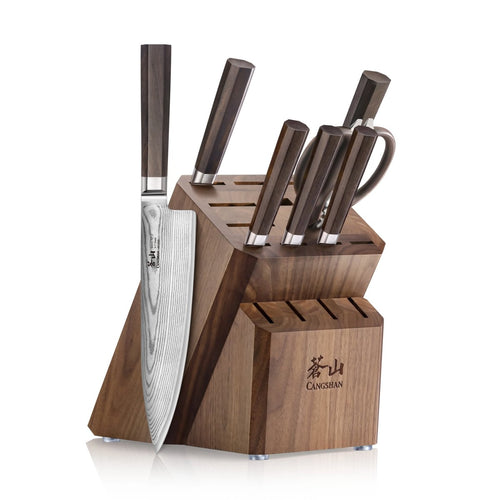 Wooden knife block holding six knives with dark handles and a pair of kitchen scissors.