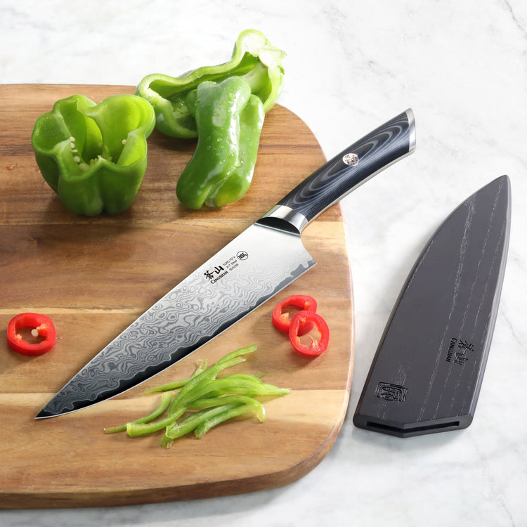 8-inch Damascus steel chef's knife with black handle on wooden board, sliced green and red bell peppers, and black sheath nea