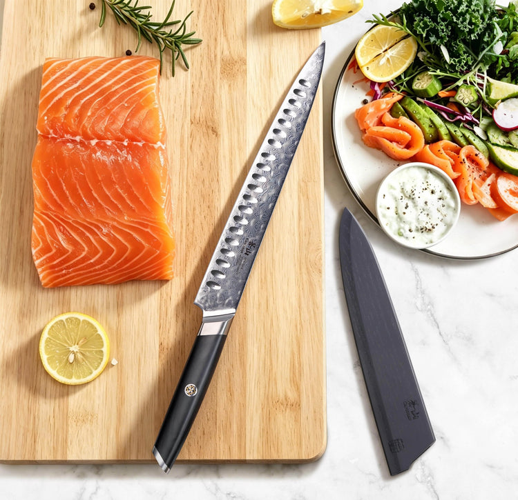 AIRA Series 10-Inch Carving Knife with 135-Layer Damax™ Steel beside a salmon fillet and salad on a cutting board.