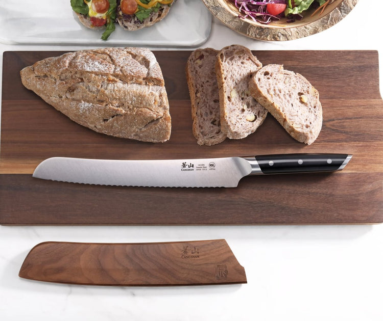 9-inch serrated bread knife with black handle on wooden cutting board next to sliced rustic bread and sheath.