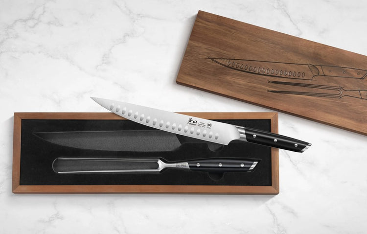 Two-piece carving set with a serrated knife and carving fork in a wooden box with a black interior lining.