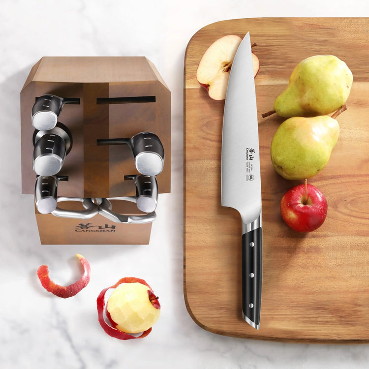 Knife block with six knives and a large chef's knife on a cutting board with pears and an apple.