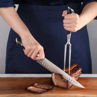 
                    
                      Person slicing a cooked meat roast on a wooden cutting board using a carving knife and fork.
                    
                  