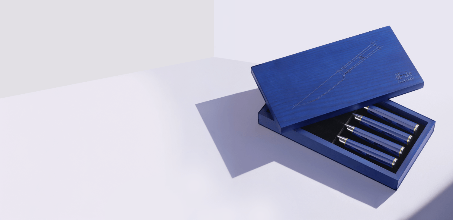 Blue wooden gift box partially open to reveal a set of four steak knives with matching blue handles.