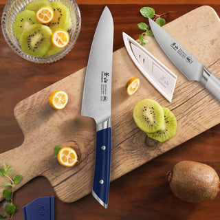 
                    
                      Two kitchen knives with navy and white handles on a wooden cutting board with sliced kiwi and kumquats.
                    
                  