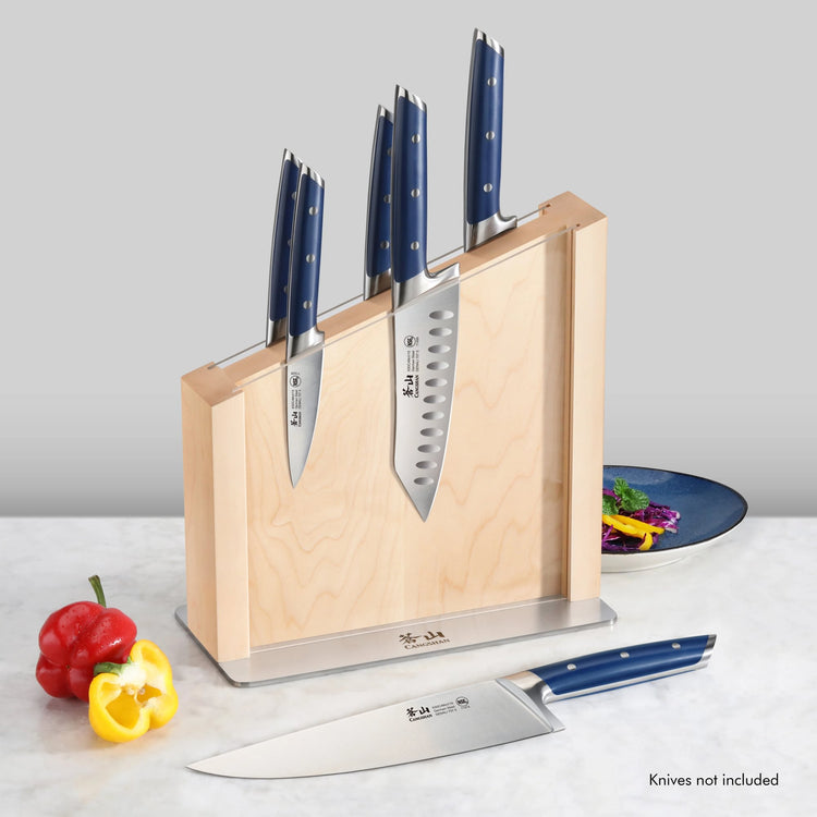 Maple magnetic knife block with clear blade guard holding four knives with blue handles, one knife lying in front.