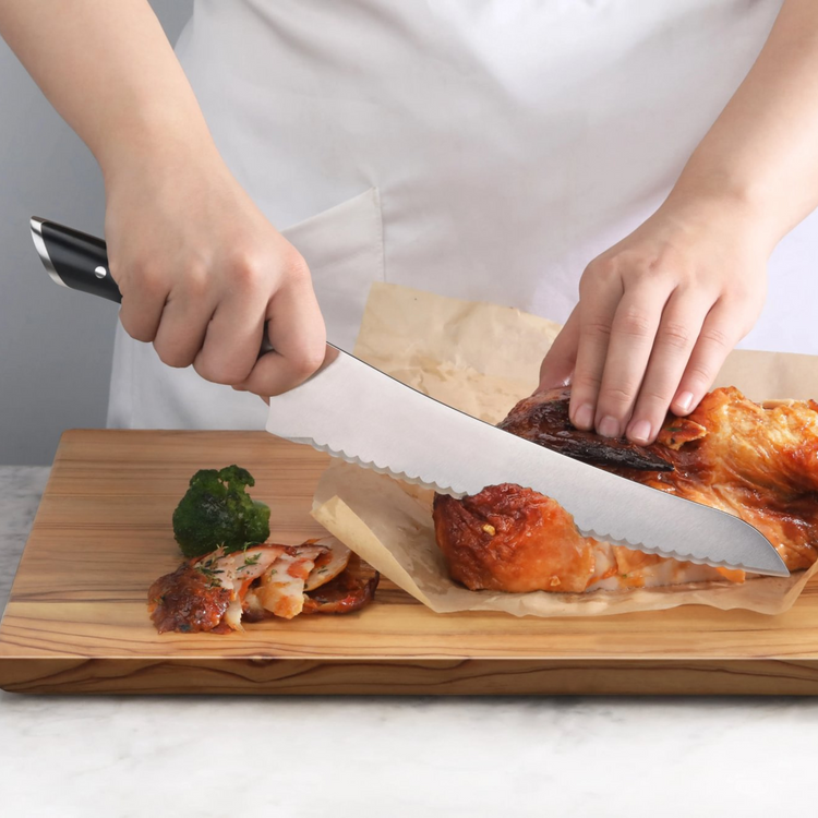 Person slicing cooked meat on a wooden board using a black-handled serrated knife.