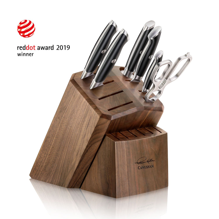 Wooden knife block holding six knives and a peeler, with eight empty slots, featuring a signature on the front.