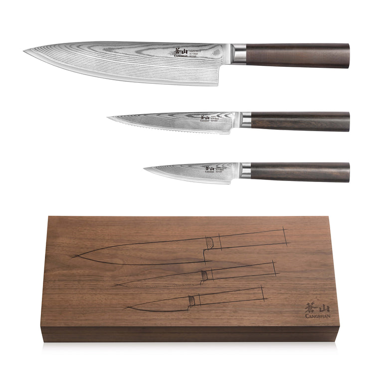 Three Damascus steel knives with dark wooden handles displayed above a matching walnut storage box with knife outlines.