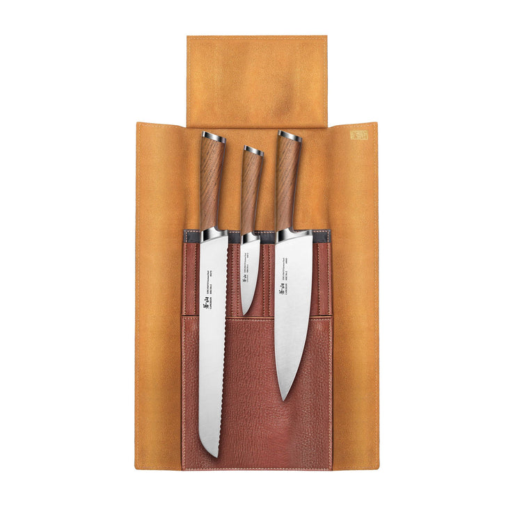 Three knives with wooden handles in a brown leather roll-up case with three stitched pockets.