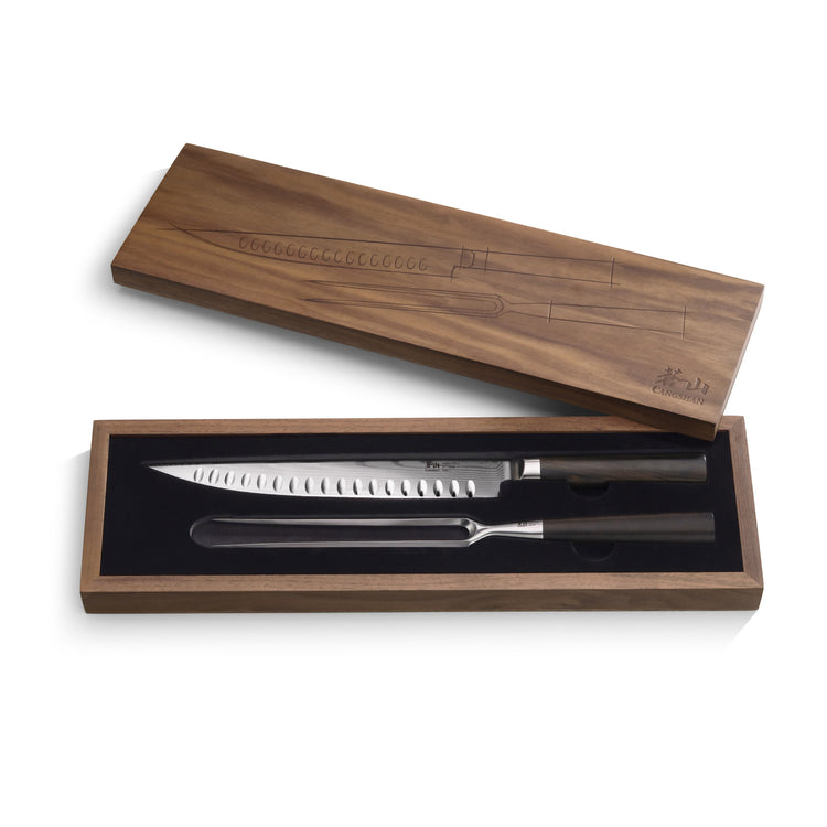 Two-piece carving set with a serrated knife and carving fork in a walnut box with engraved lid.