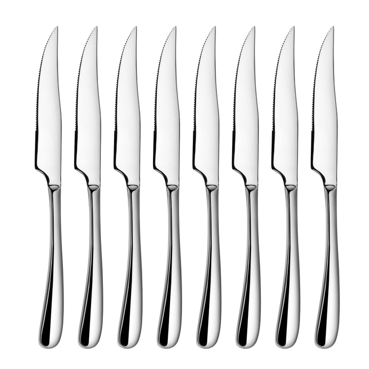 Eight stainless steel steak knives with serrated blades and polished handles arranged in a row.