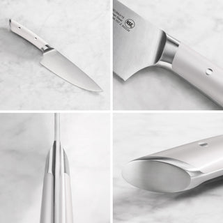 
                    
                      Chef knife with a white handle, showing full blade, handle details, and tang construction on a marble surface.
                    
                  