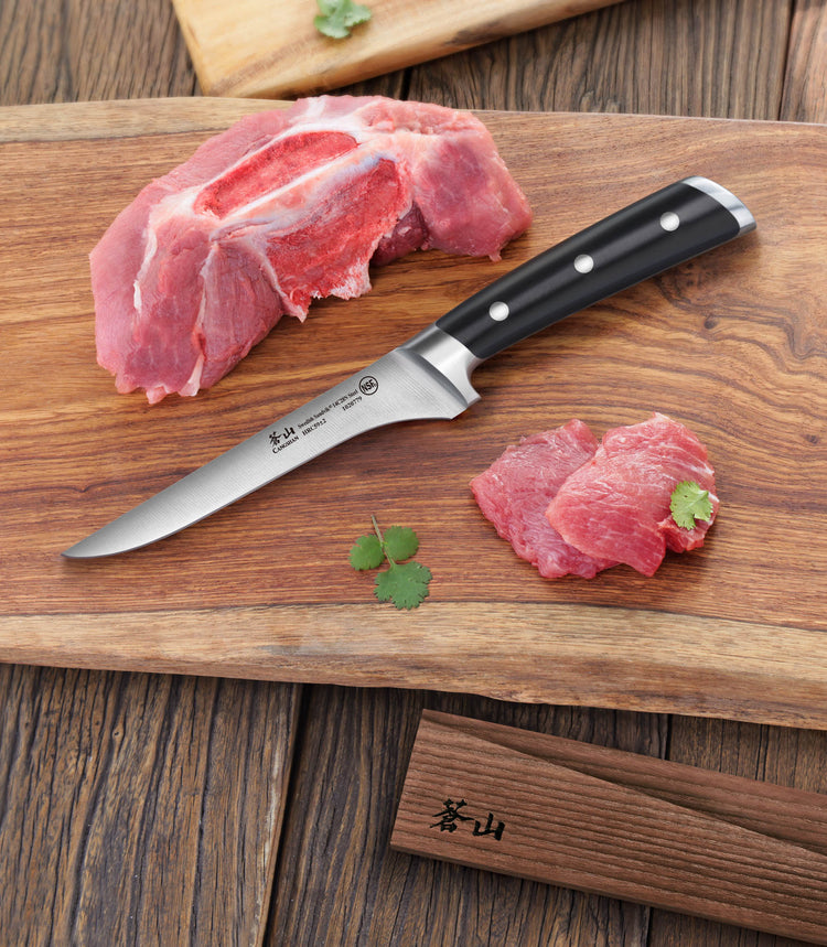 TS Series 6-inch boning knife with black handle on wooden cutting board with raw meat pieces and herb garnish.
