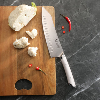 
                    
                      8-inch chef's knife with white handle on wooden cutting board next to cauliflower pieces and red chili peppers.
                    
                  
