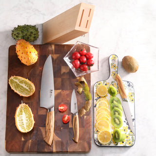 
                    
                      Four-piece knife block set with two knives on a wooden cutting board, cherry tomatoes, sliced kiwis and lemons on a floral bo
                    
                  