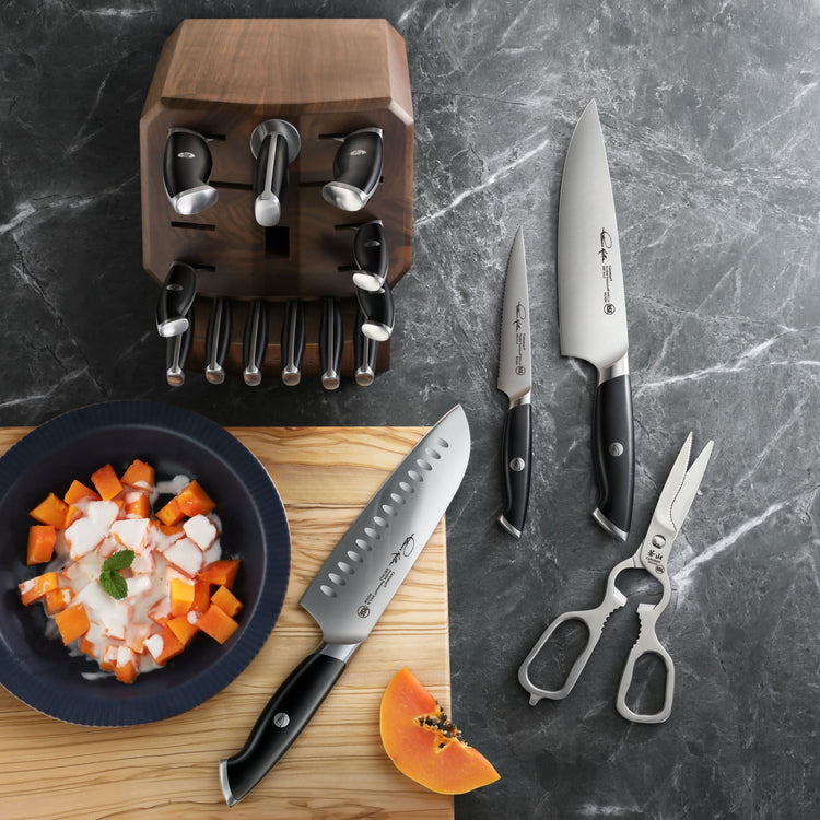17-piece knife set with wooden block, including chef, paring knives, santoku, kitchen shears, and a bowl of diced vegetables.