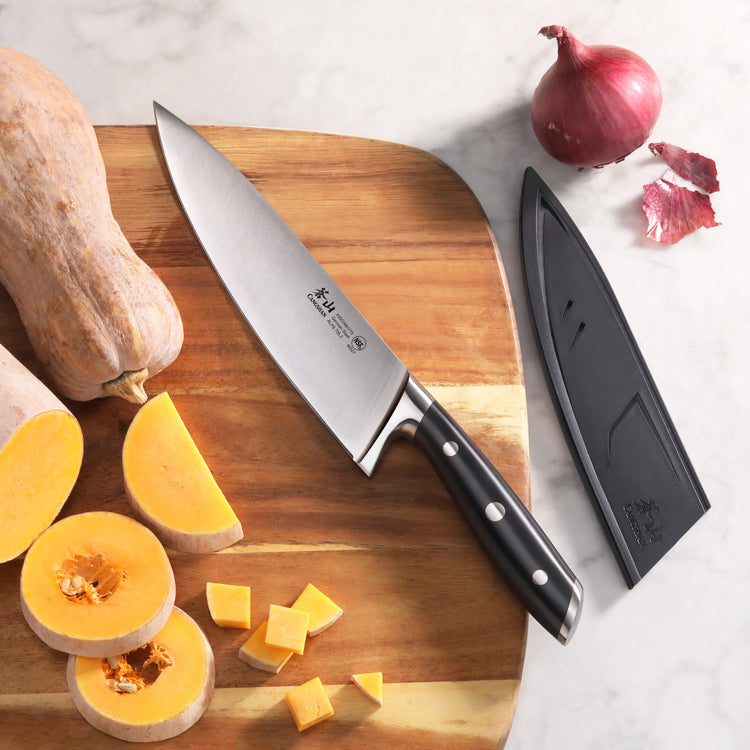8-inch chef knife with black handle and sheath on wooden cutting board with sliced squash and red onion.