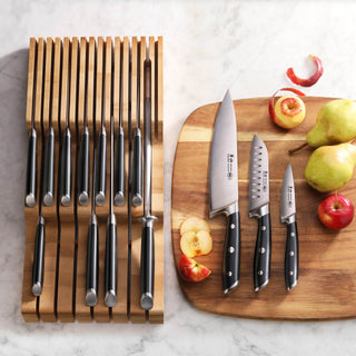 
                    
                      Fifteen black-handled knives in a bamboo in-drawer tray next to three knives on a wooden cutting board with sliced apples and
                    
                  