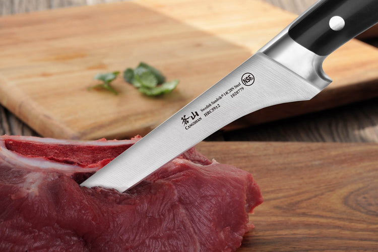 6-inch boning knife with black handle cutting raw meat on wooden surface with cutting board in background