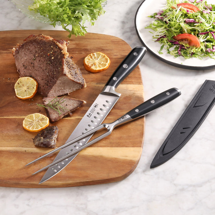 Carving knife and fork with black handles on wooden board with sliced roast beef, lemon, and salad, plus black sheath.