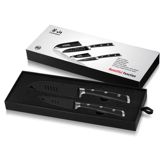 
                    
                      Two black kitchen knives with protective sheaths in a black foam tray next to a white packaging box.
                    
                  