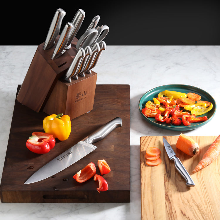 12-piece knife set in wooden block with sliced bell peppers and carrots on cutting boards.
