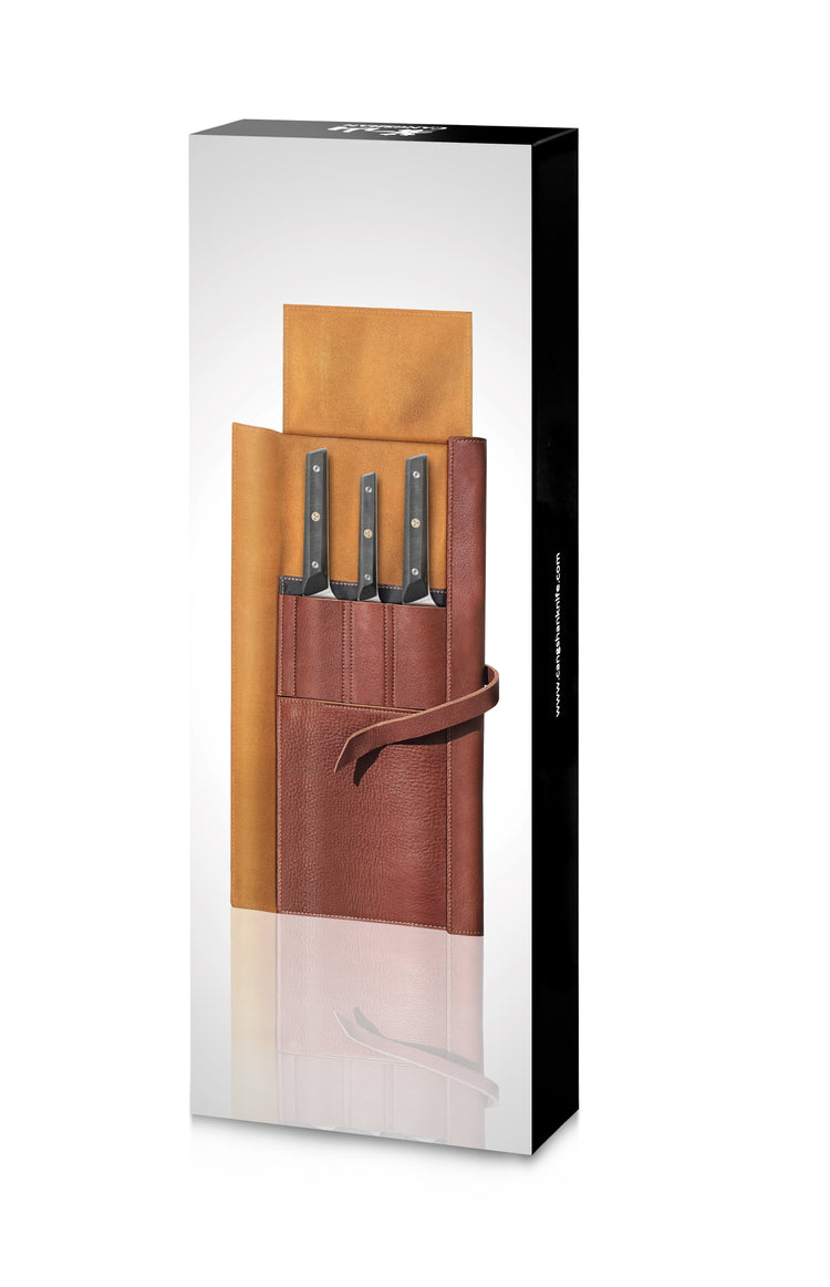 Four knives with black handles in a brown leather roll with tie closure, displayed upright on a white background.