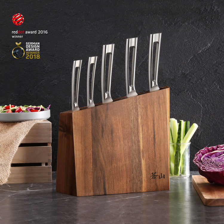 Six stainless steel knives with hollow handles in a walnut knife block on a kitchen counter.