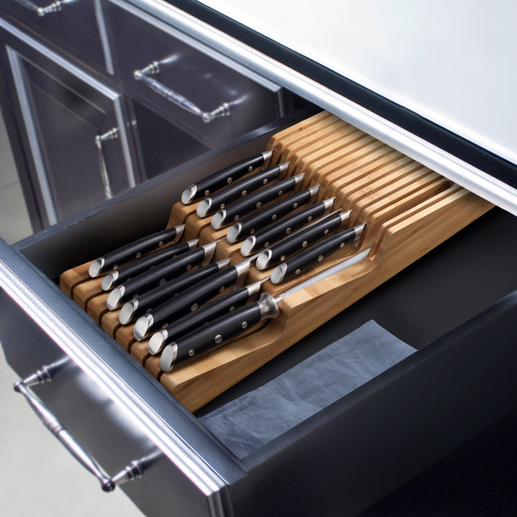 15-piece knife set with black handles neatly arranged in a bamboo in-drawer knife tray inside a kitchen drawer.