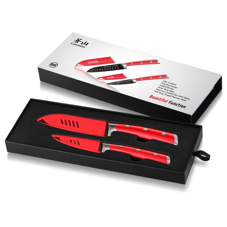 Two red-handled kitchen knives with protective sheaths in a black box, alongside the product packaging box.