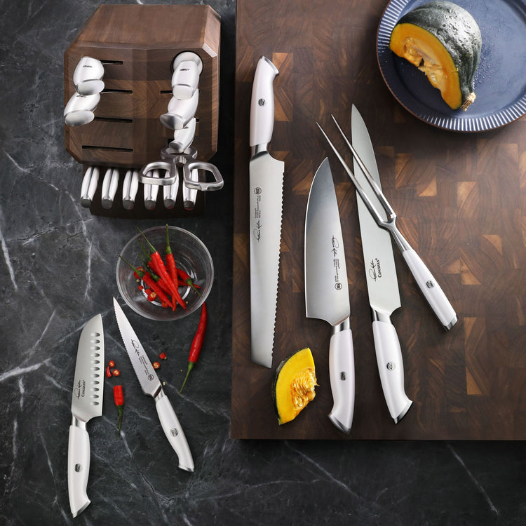 Set of white-handled kitchen knives and utensils including chef's knife, serrated knife, carving fork, and knife block on woo
